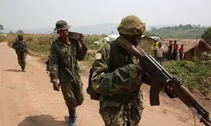 Soldater i Kongo under en tid av konflikt, bär vapen och utrustning längs en dammig väg.