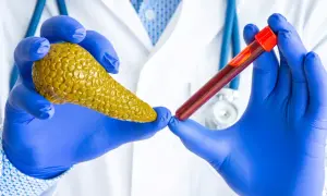 Lekarz w niebieskich rękawiczkach trzyma model trzustki i probówkę z krwią. Badanie poziomu amylazy co to jest, pomoże ocenić pracę trzustki.