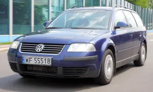 Granatowy Volkswagen Passat kombi, model b5, jedzie po drodze.