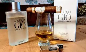 Flakon Acqua di Gio EDT, szklanka z bursztynowym płynem, cygaro i zapalniczka tworzą męski zestaw.