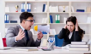 Uomo urla con megafono contro collega che si tappa le orecchie. Un chiaro esempio di **test stress da lavoro**.