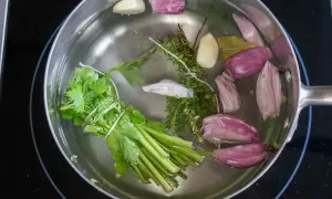 Préparation d'un court-bouillon avec oignons, ail, thym, persil et laurier. Idéal pour le temps de cuisson seiche au court-bouillon.