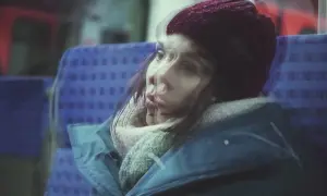 Kobieta w czapce i szaliku, siedząca w pociągu. Jej twarz jest rozmyta, jakby doświadczała amnezji dysocjacyjnej, zagubiona w myślach.