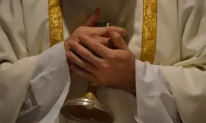 Dłonie księdza złożone nad kielichem. Złote zdobienia na szacie sugerują uroczystość, a pytanie "ile mszy może odprawić ksiądz" nabiera tu głębszego znaczenia.
