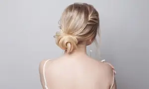 Elegancki kok z blond włosów, spięte spinką z perłą, podkreśla delikatność stylizacji.