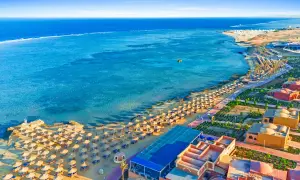 Piękna plaża z rzędami parasoli i palm, turkusowe morze i hotelowe budynki. Marsa Alam atrakcje zachwycają!