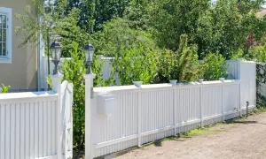 Vitt staket med brevlåda och lampor. En vacker trädgård att bygga staket i.