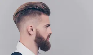 Mężczyzna z modną fryzurą i brodą. Dowiedz się, jak dbać o włosy męskie, by osiągnąć taki efekt.