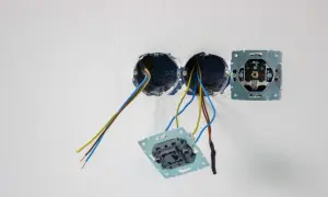 Osadzanie puszek elektrycznych w ścianie. Widać przewody wychodzące z dwóch puszek, a obok zamontowaną ramkę gniazdka.