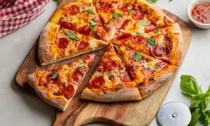 Pyszna pepperoni pizza z ciągnącym serem i świeżą bazylią, gotowa do podania na drewnianej desce.