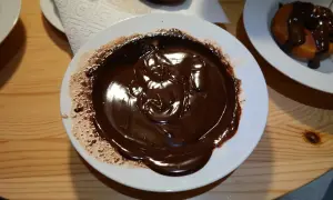 Płynna polewa czekoladowa na talerzu, gotowa do polania ciasta. Idealny moment, kiedy polać ciasto polewą czekoladową.
