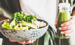 En person håller en skål med en hälsosam sallad och en grön smoothie. Perfekt bra mat gravid för näring och energi.