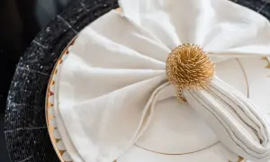 Vackert vika servetter med en gyllene ring som dekoration, redo för en festlig middag.