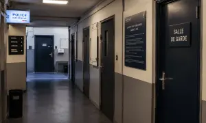 Couloir de commissariat avec des portes et un panneau "Droits des personnes en garde à vue". La fin de garde à vue approche pour certains.