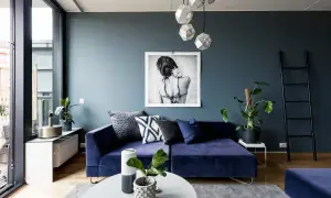 Ein tiefblauer, samtiger Sofa-Traum in azur Farbe, umgeben von modernen Deko-Elementen und einem Kunstwerk.