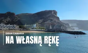 Gran Canaria zwiedzanie: malownicza plaża z hotelami i klifami w tle, błękitne morze.
