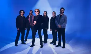 Zespół Simply Red gotowy na koncert. Muzycy pozują na tle niebieskiego światła, tworząc atmosferę nadchodzącego wydarzenia.