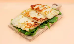 Usmażony ser halloumi na desce z rukolą.