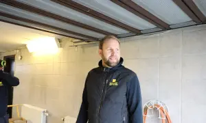 Man i väst med texten "Garageportexperten" ler. Ovanför syns en **täta garageport** i taket.