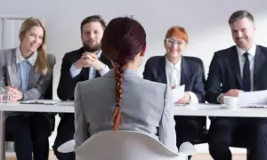 Kobieta z warkoczem siedzi przed komisją podczas rozmowy kwalifikacyjnej.
