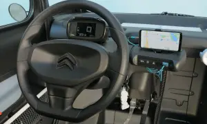 Interno Citroen Ami: volante, cruscotto digitale con indicatore di velocità e autonomia, smartphone con navigatore. La velocità massima è un dettaglio da scoprire!