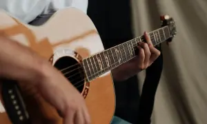 Dłoń grająca na gitarze akustycznej. Czy gra na gitarze jest trudna? Zależy od determinacji i praktyki!