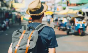 Mężczyzna w kapeluszu i z plecakiem na tle tętniącego życiem azjatyckiego miasta. Poznaj jego travel hacks!