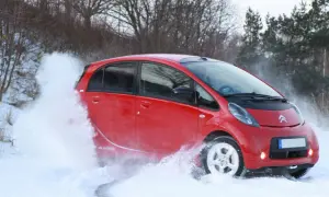Röd Citroën C-Zero kör genom snö, skapar en stor snövirvel.