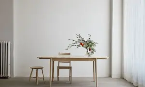 Ett ljust såpa ekbord med en vas med blommor och en pall.