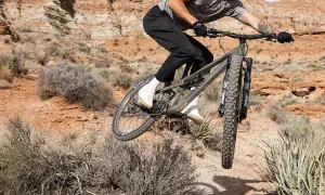 Mountainbiker auf einem Canyon Nerve AL 8.0 im Sprung in einer staubigen Wüstenlandschaft.