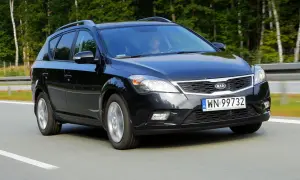 Czarny Kia Ceed 1. kombi jedzie po drodze, otoczony zielenią.