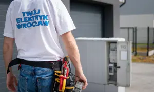 Elektryk z Wrocławia dokonuje odbioru instalacji elektrycznej. W ręku trzyma bezpiecznik, a przy pasie narzędzia.