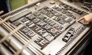 Metalowe czcionki ułożone w rzędy, gotowe do druku. Każda litera to osobny element, tworzący unikalną czcionkę.