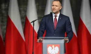 Mężczyzna w garniturze przemawia na tle flag Polski. Może właśnie użył swojego prawa weta.