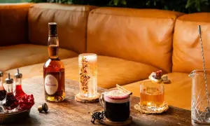 En flaska Calvados, en whisky sour med is och garnityr, en mörk drink med kanel och bär samt en bubblig dryck.