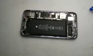 Wnętrze iPhone'a z widoczną baterią i elementami płyty głównej.