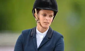 Athina Onassis w kasku i eleganckim stroju jeździeckim, skupiona na zawodach.