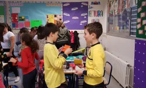 Niños participando en dinámicas de grupo en un aula, interactuando y compartiendo materiales.