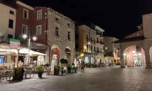 Serata nel centro storico Desenzano del Garda, con locali illuminati e tavolini all'aperto.