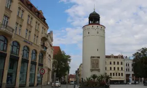 Der Reichenturm dominiert den Marienplatz Görlitz, flankiert von historischen Gebäuden und blühenden Blumenbeeten.