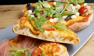 En skiva pizza napoletana med luftig deg, mozzarella, ruccola och prosciutto.