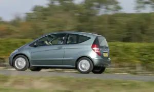 Zielony Mercedes W169 w ruchu, z rozmazanym tłem drzew i pól.