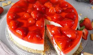 Ein köstlicher Erdbeerkuchen ohne Backen, mit frischen Erdbeeren und rotem Tortenguss auf cremigem Boden.