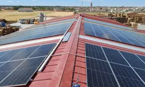 Paneles solares cubren el tejado rojo de un edificio industrial, capturando la energía del sol.