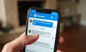 Palec dotyka ekranu telefonu z aplikacją Messenger. Dowiedz się, jak usunąć konto na Messengerze bez Facebooka.