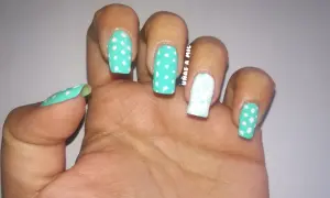 Uñas sevillanas con diseño de lunares turquesa y blanco, y un dedo decorado con un delicado estampado floral.
