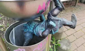 Ein bronzener Zwerg hängt kopfüber in einem Mülleimer in Hitzacker. Die Zwerge sind ein beliebtes Motiv.
