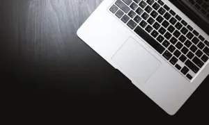 Laptop na czarnym blacie. Dowiedz się, jak otworzyć plik rar, korzystając z klawiatury i touchpada.