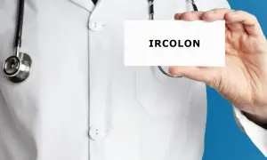 Lekarz w białym kitlu prezentuje kartkę z napisem IRCOLON. Stetoskop wisi na jego szyi.