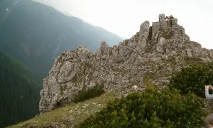 Sarnia skała szlak z Zakopanego. Grupa turystów na szczycie skalistego wzniesienia, w tle gęsty las i mgliste góry.